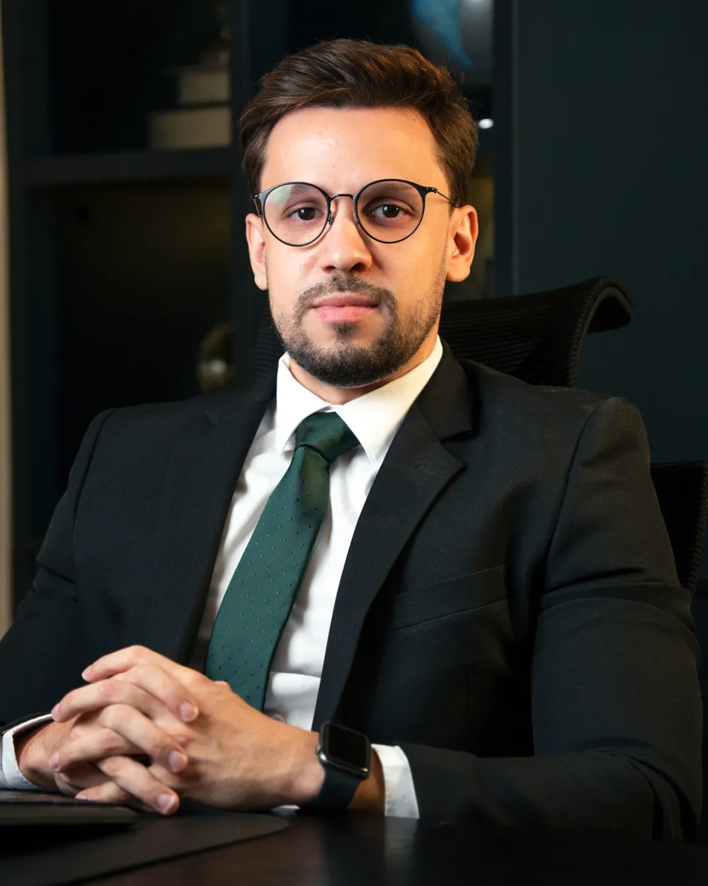Gabriel Gondim Rodrigues sentado à mesa do escritório, de terno escuro